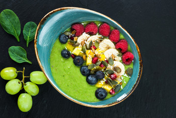 Green avocado, spinach and grape smoothie garnished with fresh fruit