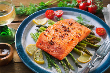 Grilled salmon garnished with green asparagus and tomatoes