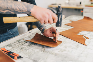 Close up of a leather craftsman working with leather using hammer. Leather handmade.