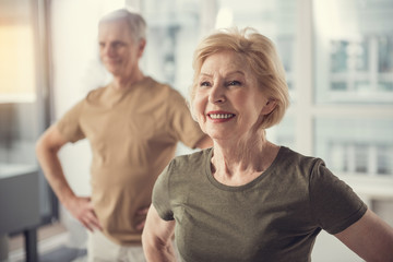 Portrait of content good looking old lady in studio. Aging male on background