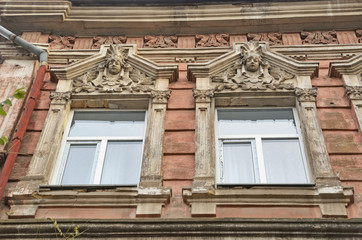 Windows with allegorical female head sculptural decorations and hood molds in an old building in the historical center of Mykolaiv City, Ukraine