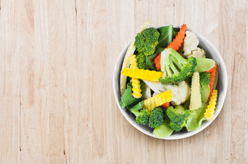 Fresh vegetables in white bowl on wooden background