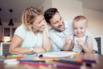 Mam and dad  with child drawing at home