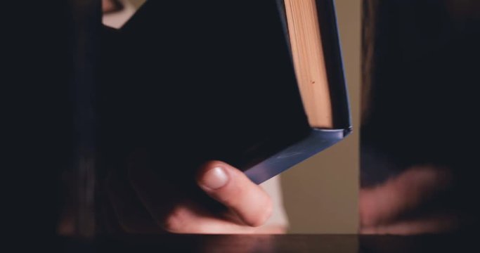 The man takes the book from the shelf and flips through it.