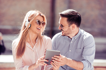 Couple listening music together while sitting in a city.