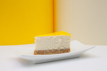 One piece of lemon cheesecake on a white plate.