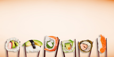 Traditional japanese sushi pieces placed between chopsticks on pastel color background.