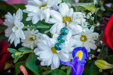 Jewelry in a flowers bouquet. Fashion and design jewelry. Bijouterie on a background of flowers. Accessorize for creating a fashionable style and image. Bijouterie for a spring 