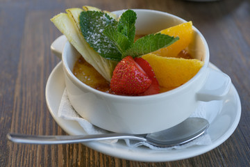 Caramel dessert with fresh fruits in a snow-white porcelain Cup.