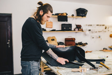 Working process of the leather bag in the leather workshop. Сrafting tool on work table background.