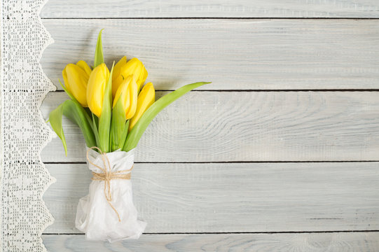 Bouquet of yellow tulips on white wooden table