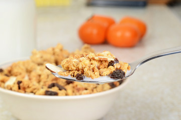 macro granola raisin almond cereal with milk on a spoon