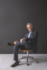 Full length portrait of happy mature male sitting on comfortable seat. Glad resting employer concept