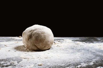 Pizza dough or baking on a dark black background of wood. Baking bread, pizza, pasta. Recipe from chef cooks pizza. Italian home cooking. Top view, horizontal photo
