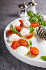 Delicious caprese salad with ripe cherry tomatoes and mini mozzarella cheese balls with fresh basil leaves. Italian healthy food concept with copy space.