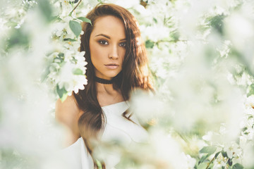 Beautiful young woman surrounded by flowers of apple-tree