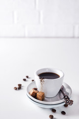 cup of black coffee on a saucer with brown sugar on a white background
