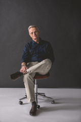 Full length portrait of happy old businessman sitting on comfortable chair. Glad resting employer...