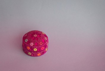 Multicolored box decorated with small stones on the blue background. Flat lay. Minimal concept.