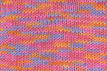 background of multicolored knitted fabric in pink, orange and lilac