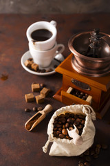Coffee grinder , cup of coffee and coffee beans bag in background.