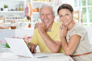 senior man with adult daughter using laptop
