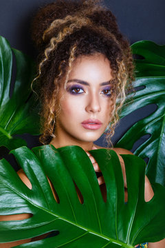 Close-up Portrait of an African American Black Woman with evening make-up and tropical leaves on black background