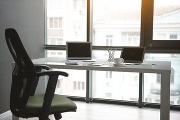 Modern notebook computers, mug of coffee and copybook situating on table. Interior of office concept