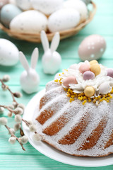 Easter cake with eggs and ceramic rabbits on mint wooden table