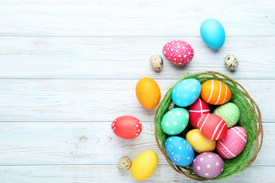 Colorful easter eggs in basket on wooden table