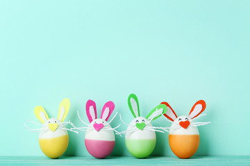 Eggs with funny rabbit faces on mint background
