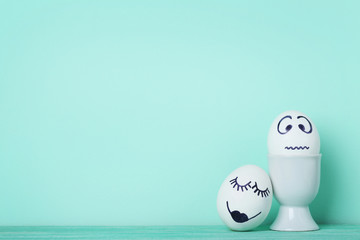 Eggs with funny faces on mint background
