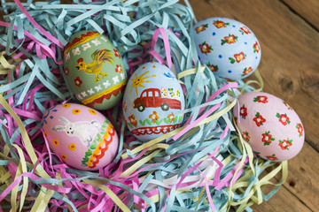 Painted eggs lie in a basket, wooden background, easter