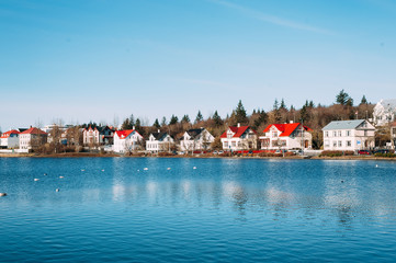 colorful houses on the shore of reykjavik lake - obrazy, fototapety, plakaty