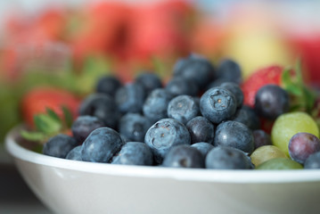 White bowl of fresh healthy fruit salad on wooden background
