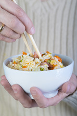 Comiendo arroz frito tres delicias de los restaurantes chinos con palillos, comida china de España