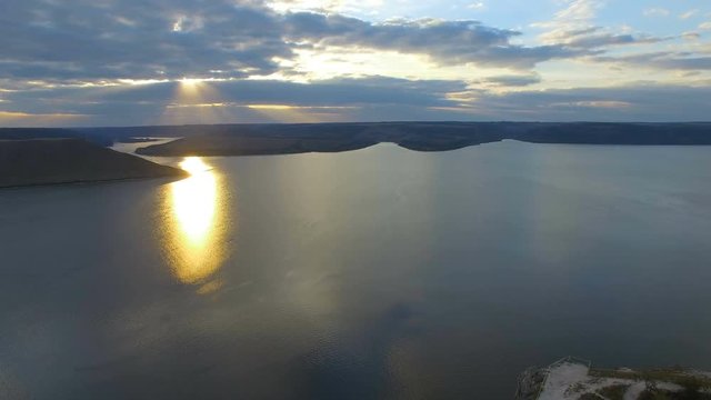 Great sunset on the lake between the mountains. A couple hugging at the edge of the cliff. 4k