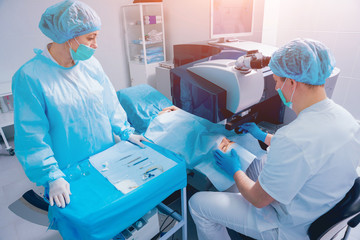 Laser vision correction. A patient and team of surgeons in the operating room during ophthalmic...