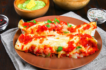 Homemade chicken enchiladas in dish on wooden table. Top view.