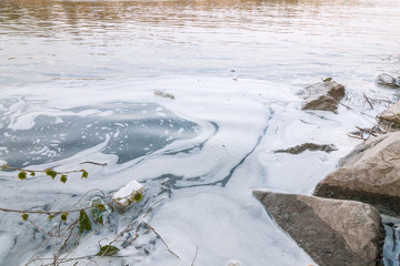 Polluted river, foam in a water near shore.