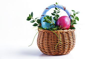 Colorful Easter eggs in a small Easter basket on a white background