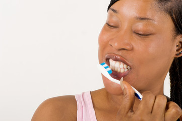 close up young woman brushing teeth happily isolated on light background