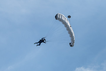 Parachutist with White Parachute against Clear Blue Sky
