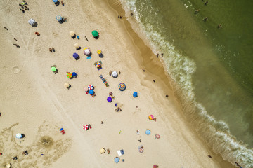 People on the beach. Top aerial view with ocean and colorful umbrellas