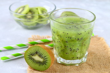 Sliced kiwi and smoothie slices in a glass on a gray table. Healthy food.
