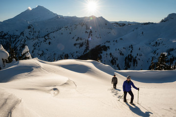 Couple friends are snowshoeing in fresh snow surrounded by the beautiful American Landscape. Taken in Artist Point near Mount Baker, Northeast of Seattle, Washington, USA.