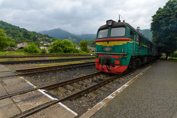 Fototapeta premium The old green locomotive stands at the railway station. In mountainous terrain