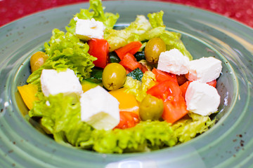 Caesar salad with olives and cheese on a plate close up