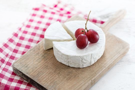 Soft Cheese wheel with a piece of cheese on a wooden board 