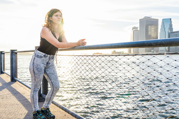 Young woman standing outside outdoors in NYC New York City Brooklyn Bridge Park by east river,...